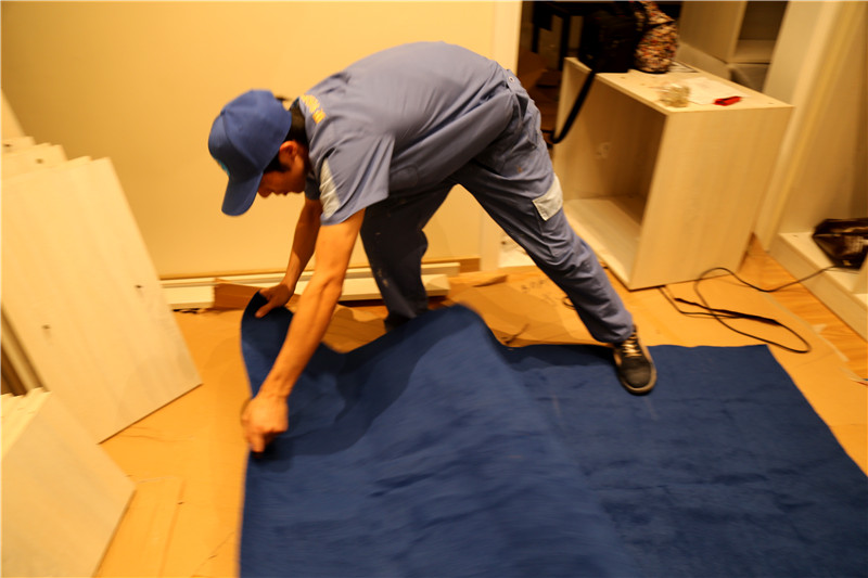 左右手家具安装师傅为了保护客户家的地板不被损坏，每一位师傅都备有一条蓝色的地毯