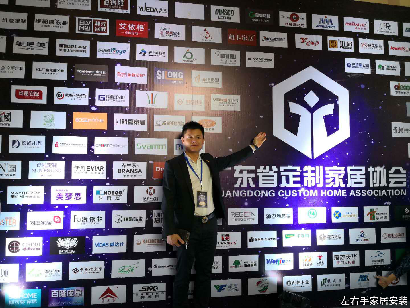 左右手家居安装创始人卢建华先生在2018广州定制家具峰会会员企业名单墙拍照留念